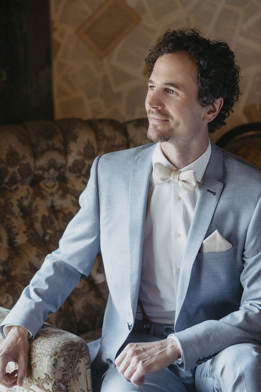 Mann mit Set Fliege Einstecktuch aus Leinen in Sandfarbe Beige Camillo kombiniert mit hellblauem Anzug FAFIGO